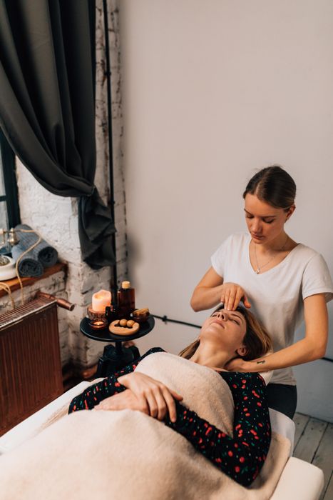 Woman receiving calming facial massage in serene indoor spa setting.